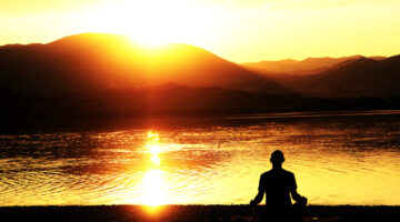 Silhouette of a man meditating on a lakeshore